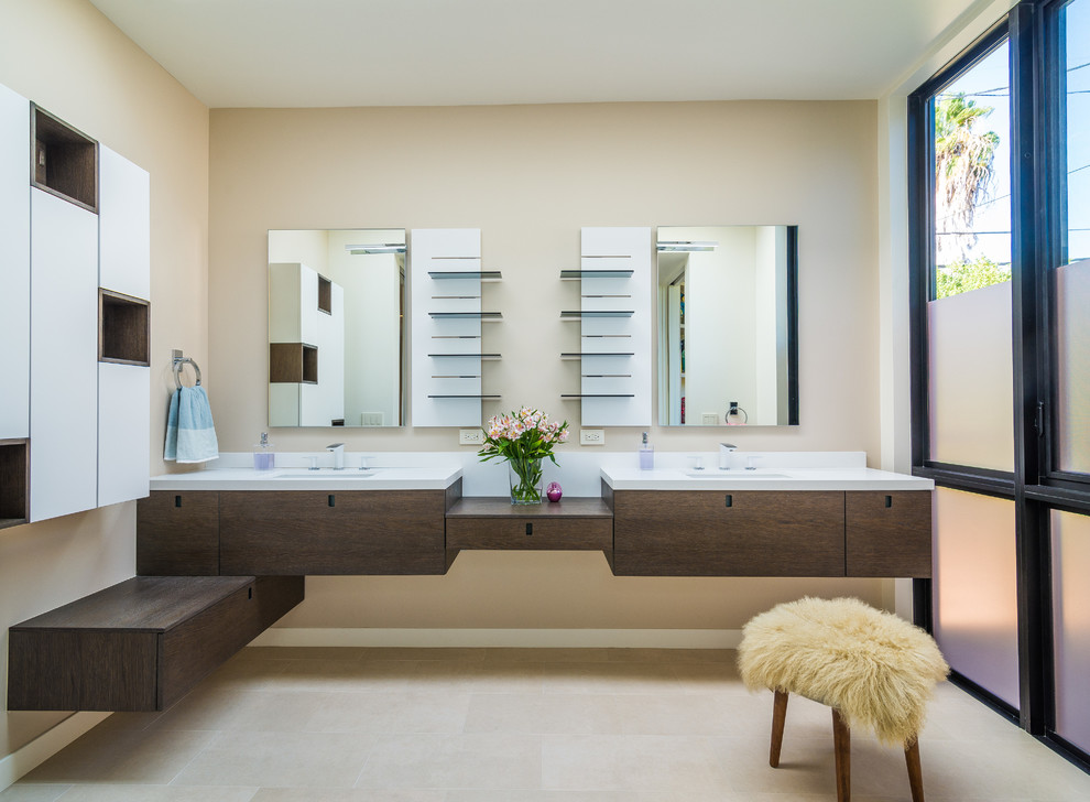 Design ideas for a mid-sized contemporary 3/4 bathroom in Los Angeles with flat-panel cabinets, dark wood cabinets, a drop-in tub, a shower/bathtub combo, a one-piece toilet, beige tile, ceramic tile, beige walls, ceramic floors, an undermount sink and marble benchtops.