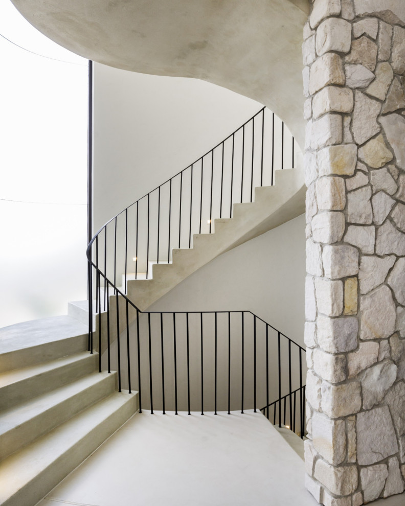 Пример оригинального дизайна: изогнутая бетонная лестница в стиле модернизм с бетонными ступенями и металлическими перилами