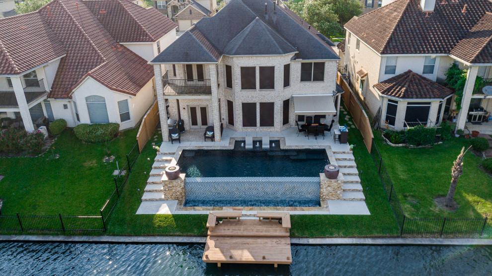 Photo of a large contemporary back rectangular infinity swimming pool in Houston with decking.