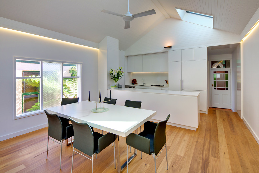 Photo of a mid-sized contemporary kitchen/dining combo in Sydney with white walls and light hardwood floors.
