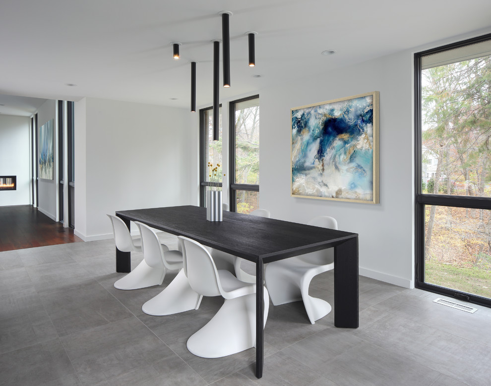 This is an example of a modern dining room in Milwaukee with white walls and grey floor.