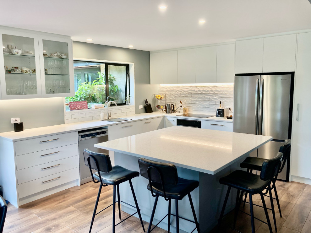Large contemporary kitchen in Christchurch with engineered stone countertops, white splashback, porcelain splashback and white worktops.