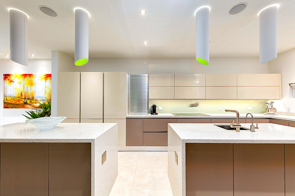 Huge transitional l-shaped porcelain tile open concept kitchen photo in Calgary with an undermount sink, flat-panel cabinets, beige cabinets, quartz countertops, green backsplash, glass sheet backsplash and two islands