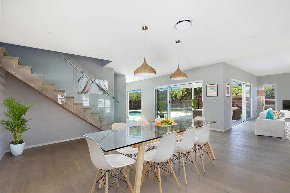 Inspiration for a mid-sized beach style open plan dining in Sunshine Coast with grey walls, light hardwood floors and brown floor.
