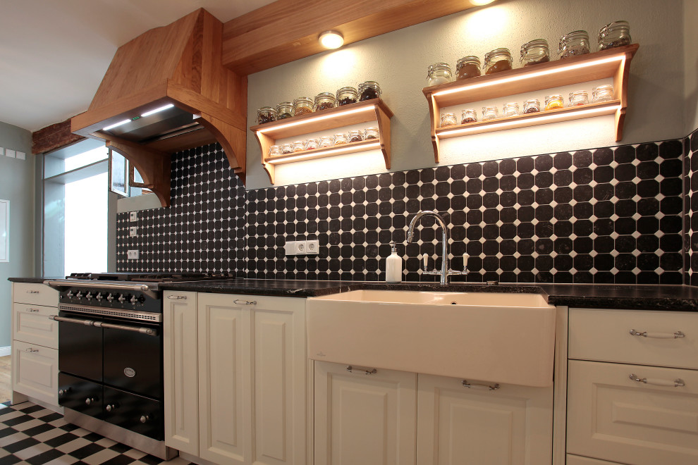 Idéer för stora lantliga brunt kök, med en rustik diskho, luckor med profilerade fronter, vita skåp, träbänkskiva, svart stänkskydd, stänkskydd i stenkakel, svarta vitvaror, kalkstensgolv och svart golv