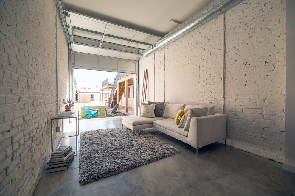 This is an example of a mid-sized industrial loft-style living room in St Louis with concrete floors.