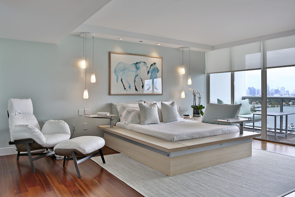 This is an example of a mid-sized contemporary master bedroom in Miami with medium hardwood floors, no fireplace, blue walls and orange floor.