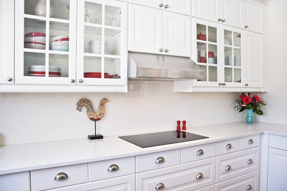 Example of a transitional eat-in kitchen design in Ottawa with an undermount sink, raised-panel cabinets, white cabinets, quartz countertops, white backsplash, porcelain backsplash, stainless steel appliances and an island