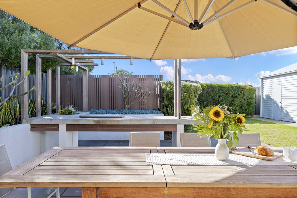 Modelo de terraza planta baja marinera en patio trasero con cocina exterior
