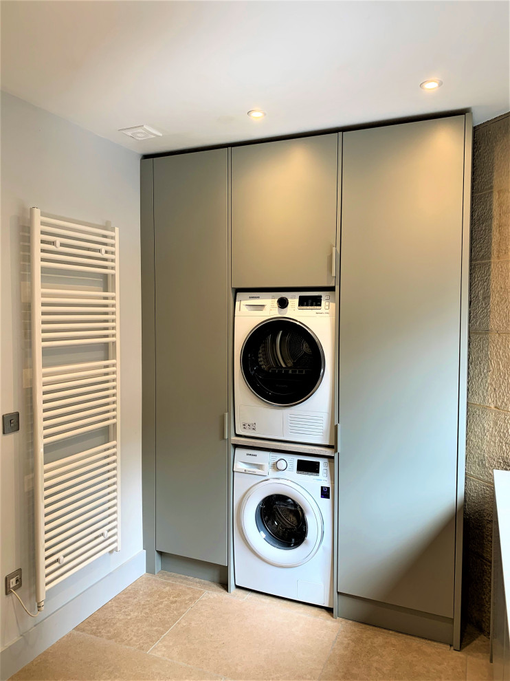 Inspiration for a mid-sized contemporary utility room in Other with a single-bowl sink, medium wood cabinets, laminate benchtops, grey walls, limestone floors and a stacked washer and dryer.