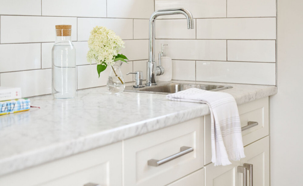 Example of a mid-sized transitional u-shaped vinyl floor and brown floor eat-in kitchen design with an undermount sink, shaker cabinets, white cabinets, marble countertops, white backsplash, subway tile backsplash, an island and gray countertops