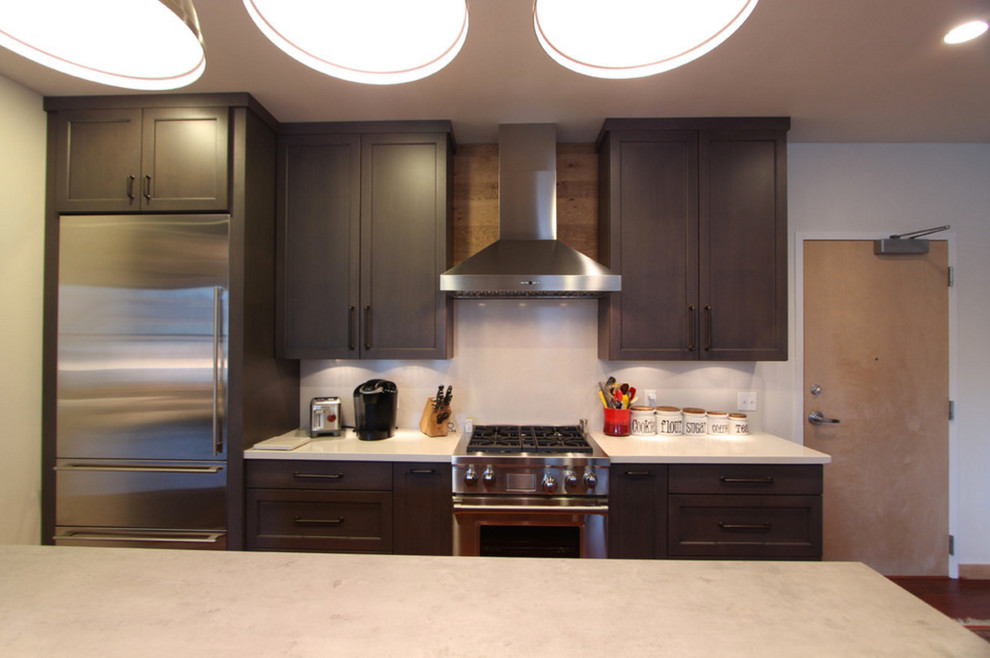 Photo of a mid-sized industrial l-shaped kitchen in Other with flat-panel cabinets, light wood cabinets, concrete benchtops, stainless steel appliances, dark hardwood floors, with island, red floor, grey benchtop and an undermount sink.