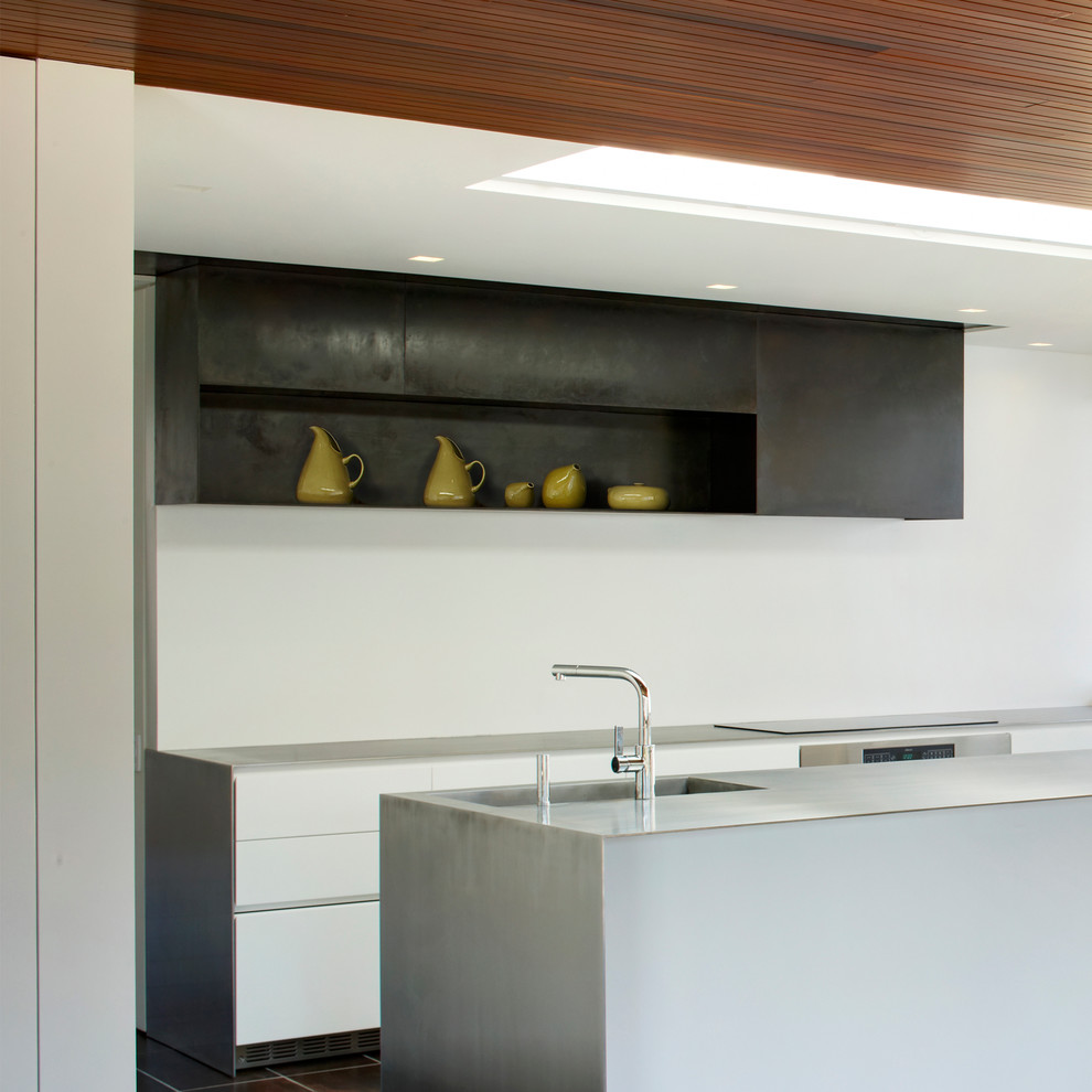 Modern kitchen in New York with flat-panel cabinets, white cabinets and white splashback.