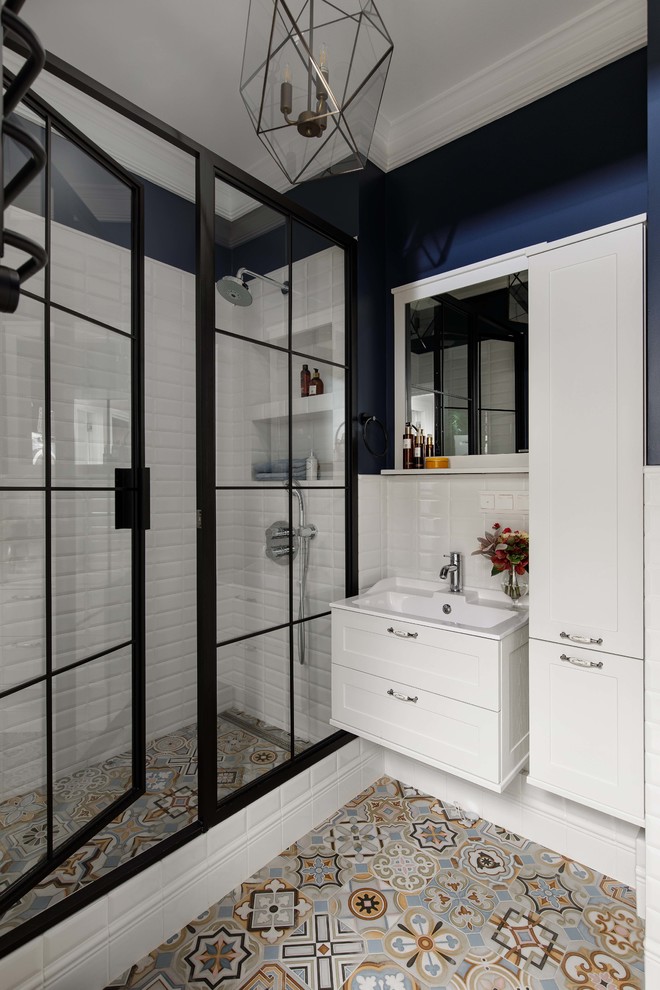 Photo of a mid-sized transitional 3/4 bathroom in Moscow with white tile, ceramic tile, ceramic floors, multi-coloured floor, blue walls, a hinged shower door, shaker cabinets, white cabinets and a console sink.