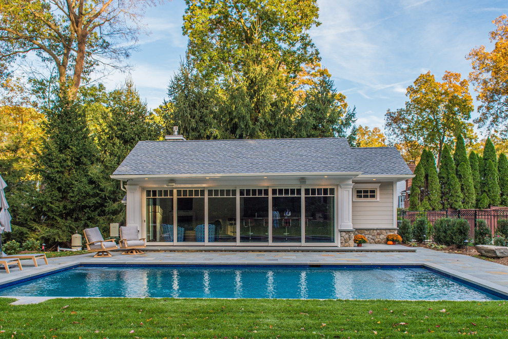 Inspiration for a large traditional backyard rectangular natural pool in New York with a pool house and natural stone pavers.