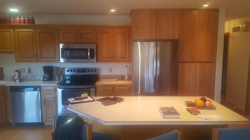 Example of a transitional light wood floor and beige floor kitchen pantry design with a double-bowl sink, raised-panel cabinets, light wood cabinets, laminate countertops, stainless steel appliances, an island and white countertops