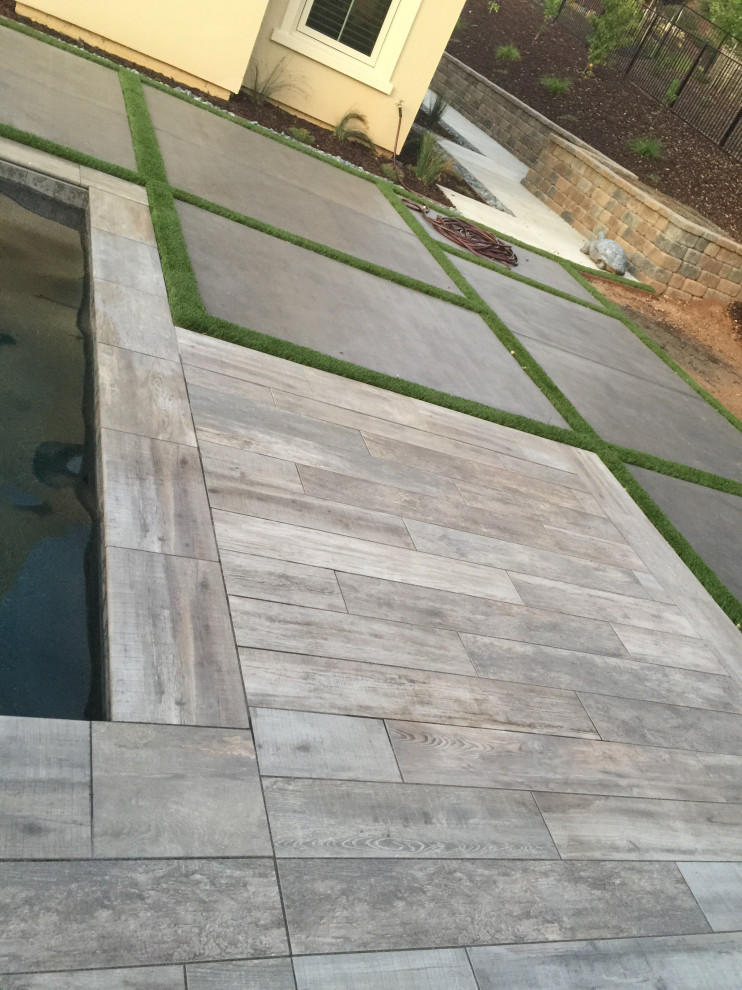 Large classic back rectangular swimming pool in Sacramento with with pool landscaping and concrete slabs.