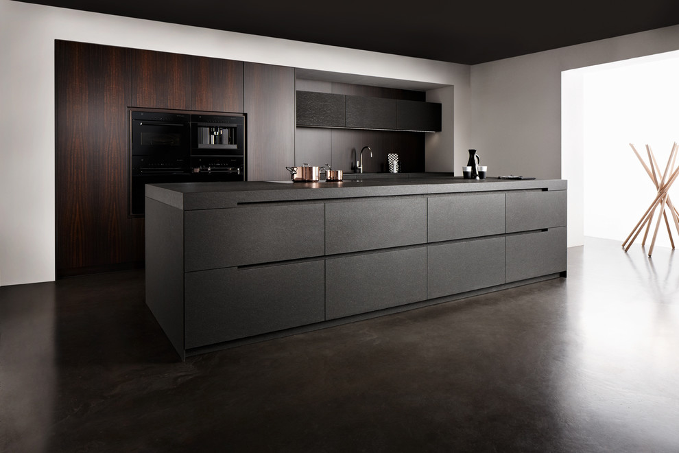 Inspiration for a mid-sized contemporary kitchen in London with an integrated sink, flat-panel cabinets, dark wood cabinets, granite benchtops, brown splashback, black appliances, concrete floors and with island.