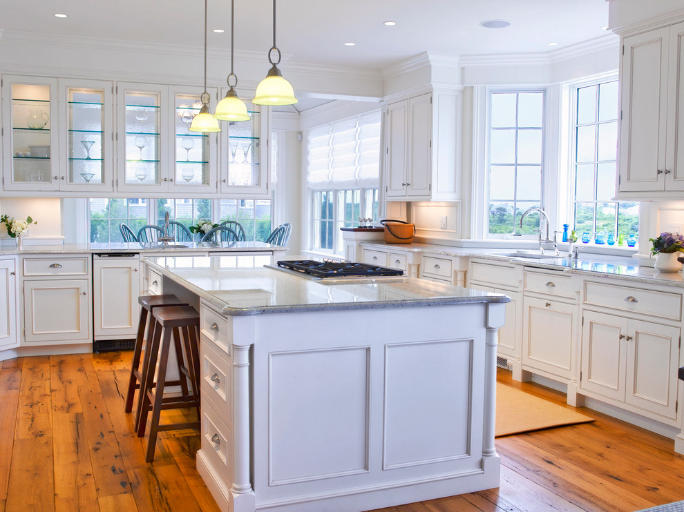 This is an example of a traditional u-shaped eat-in kitchen with an undermount sink, recessed-panel cabinets, white cabinets, medium hardwood floors and with island.