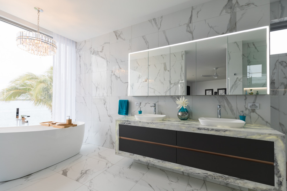 ゴールドコーストにあるコンテンポラリースタイルのおしゃれな浴室 (置き型浴槽、白いタイル、白い壁、大理石の洗面台、黒い床、洗面台2つ、フローティング洗面台) の写真
