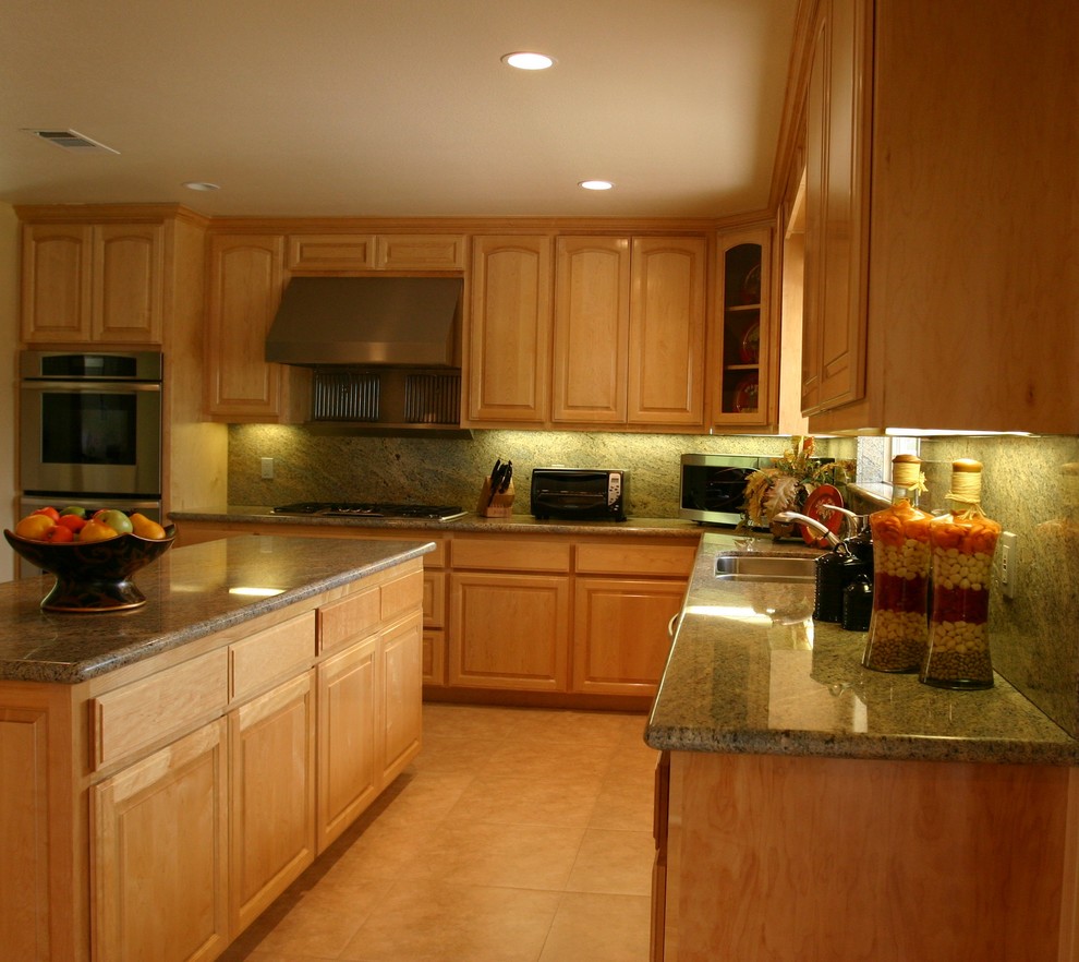 Inspiration for a large traditional l-shaped separate kitchen in San Francisco with a double-bowl sink, raised-panel cabinets, light wood cabinets, granite benchtops, green splashback, stone slab splashback, stainless steel appliances, limestone floors, with island, beige floor and green benchtop.