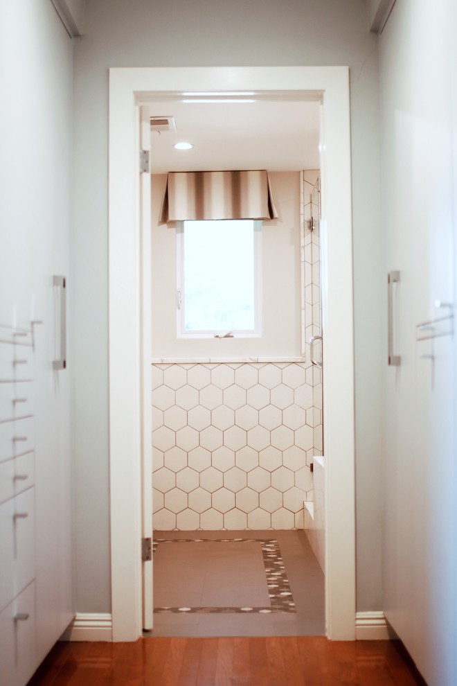 This is an example of a small modern women's dressing room in Los Angeles with flat-panel cabinets, grey cabinets, medium hardwood floors and brown floor.
