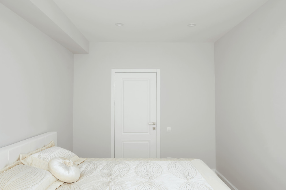 Immagine di una camera matrimoniale minimal di medie dimensioni con pareti bianche, pavimento in laminato, nessun camino, pavimento marrone e carta da parati