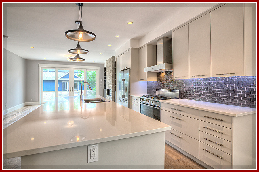 Inspiration for a mid-sized single-wall medium tone wood floor open concept kitchen remodel in Calgary with a double-bowl sink, flat-panel cabinets, white cabinets, quartzite countertops, gray backsplash, glass tile backsplash, stainless steel appliances and an island