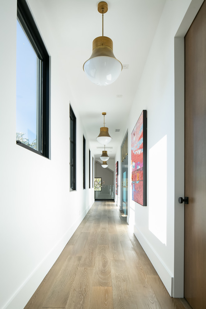 This is an example of a contemporary hallway in Orange County with white walls, medium hardwood floors and brown floor.