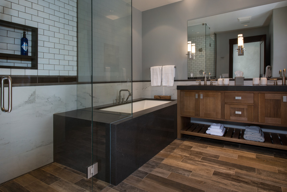 Photo of a large transitional kids bathroom in Denver with shaker cabinets, brown cabinets, an undermount tub, a curbless shower, a one-piece toilet, white tile, porcelain tile, grey walls, porcelain floors, an undermount sink, engineered quartz benchtops, brown floor and a hinged shower door.