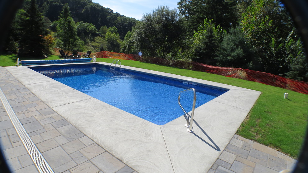 Example of a large minimalist backyard stamped concrete and rectangular pool design