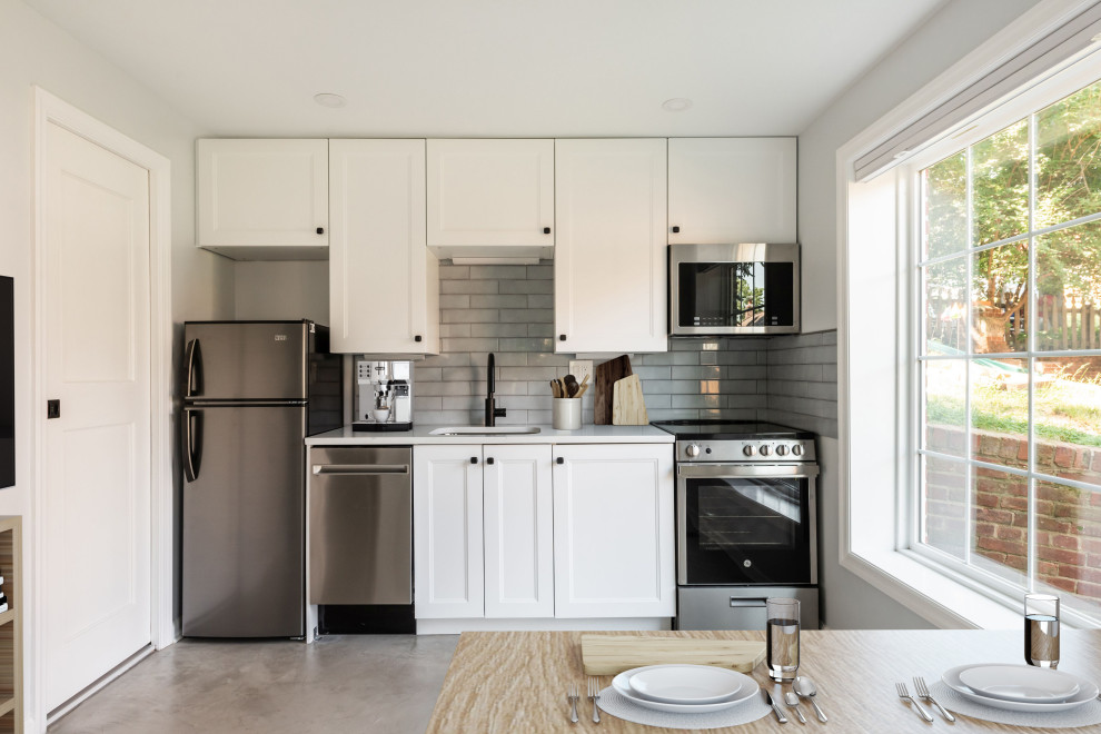 Small trendy single-wall concrete floor and gray floor eat-in kitchen photo in DC Metro with an undermount sink, shaker cabinets, white cabinets, quartz countertops, gray backsplash, ceramic backsplash, stainless steel appliances and white countertops