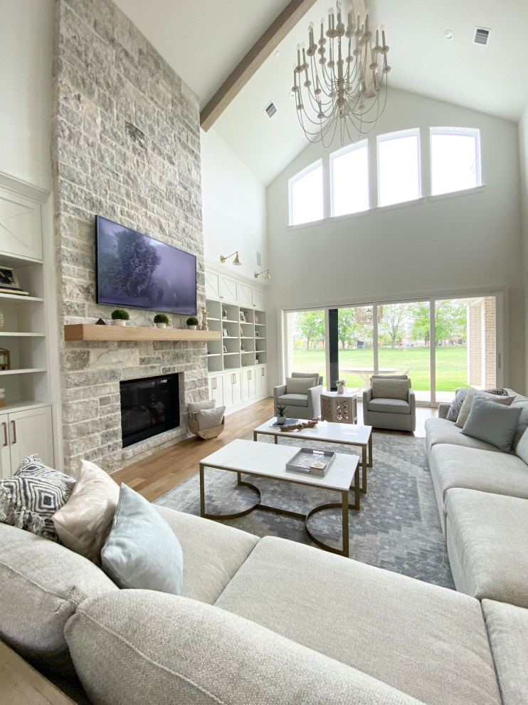 Example of a huge danish open concept light wood floor, beige floor and exposed beam family room design in Dallas with white walls, a stone fireplace and a wall-mounted tv
