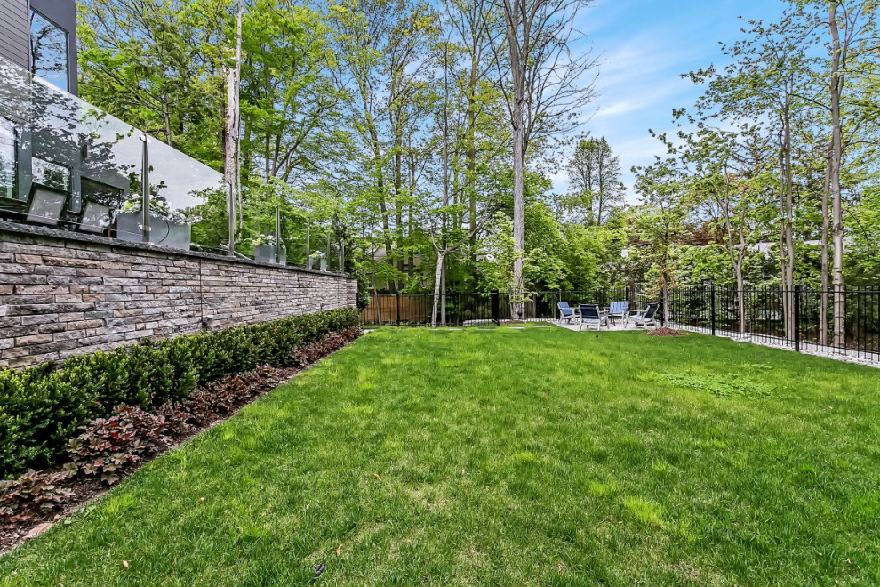 This is an example of a large transitional partial sun backyard stone formal garden in Toronto with a fire pit.
