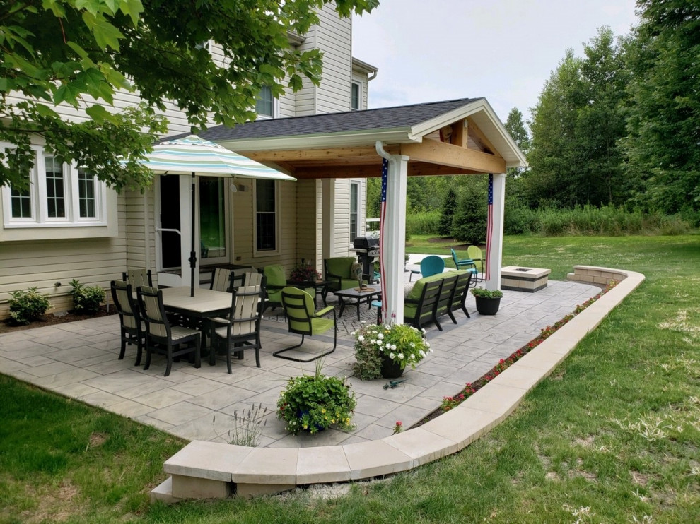 Foto di un ampio patio o portico boho chic dietro casa con un focolare, cemento stampato e un tetto a sbalzo