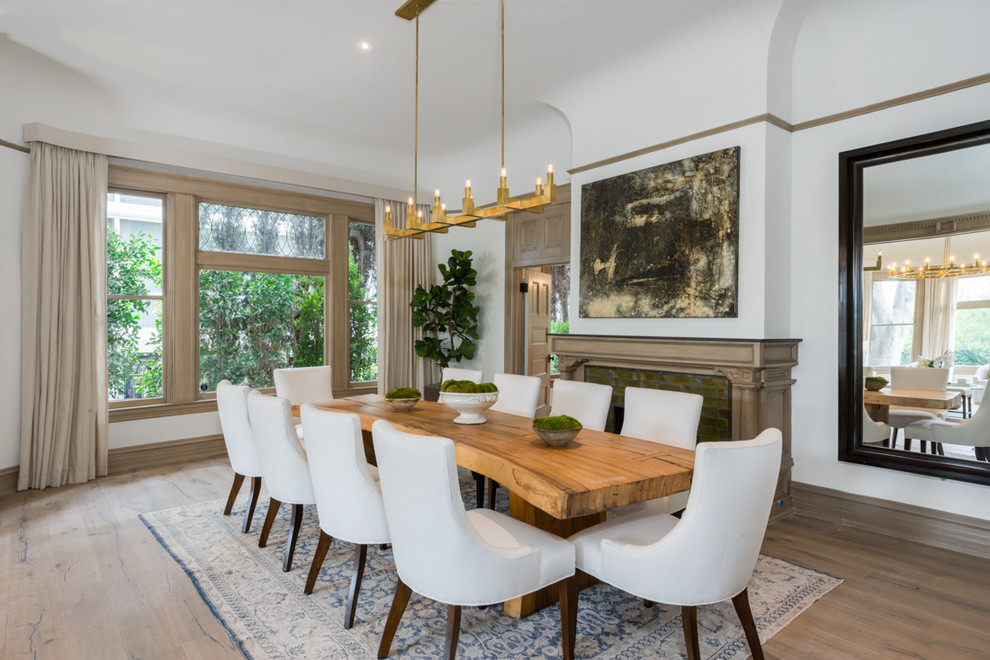 Design ideas for a traditional dining room in Los Angeles with white walls, light hardwood floors and a standard fireplace.