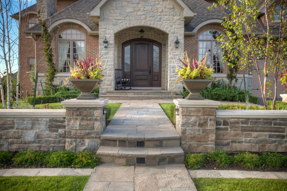 Large country front yard full sun garden in Toronto with a garden path and natural stone pavers for summer.