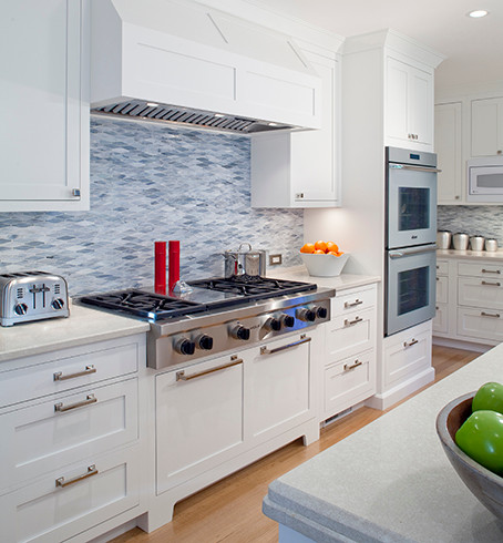 This is an example of a mid-sized country u-shaped eat-in kitchen in Boston with an undermount sink, shaker cabinets, white cabinets, marble benchtops, blue splashback, marble splashback, stainless steel appliances, light hardwood floors, with island and brown floor.
