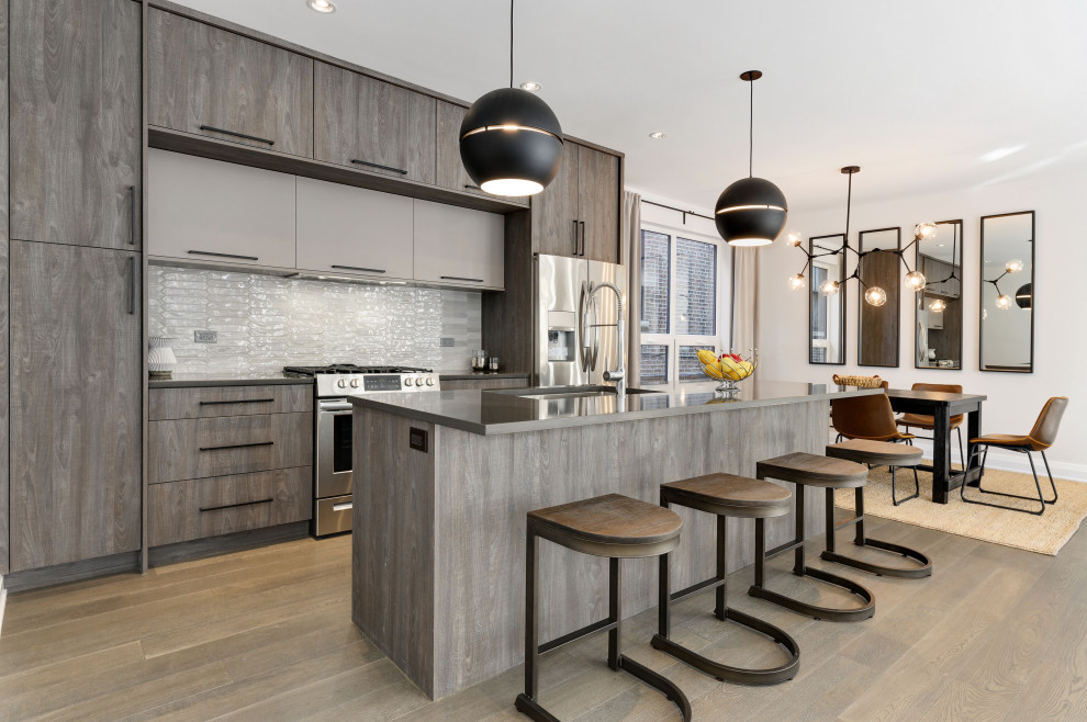 Inspiration for a contemporary galley kitchen in Chicago with an undermount sink, flat-panel cabinets, dark wood cabinets, white splashback, stainless steel appliances, dark hardwood floors, with island, brown floor and grey benchtop.