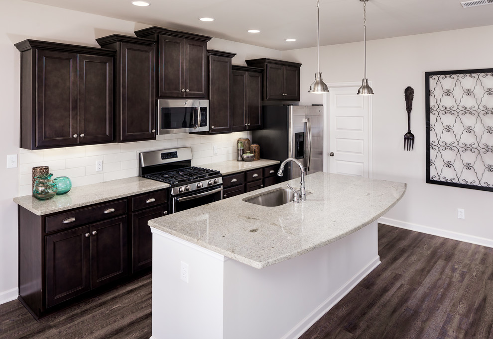 Inspiration for a mid-sized transitional single-wall medium tone wood floor eat-in kitchen remodel with an undermount sink, shaker cabinets, dark wood cabinets, granite countertops, white backsplash, subway tile backsplash, stainless steel appliances and an island