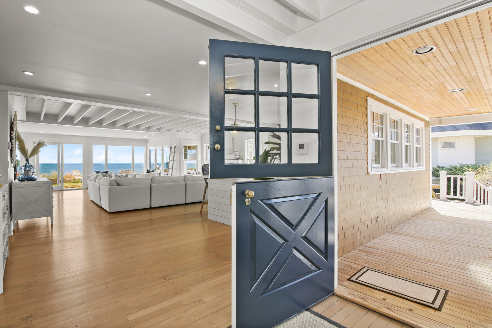Photo of a mid-sized beach style front door in New York with white walls, light hardwood floors, a dutch front door and a blue front door.