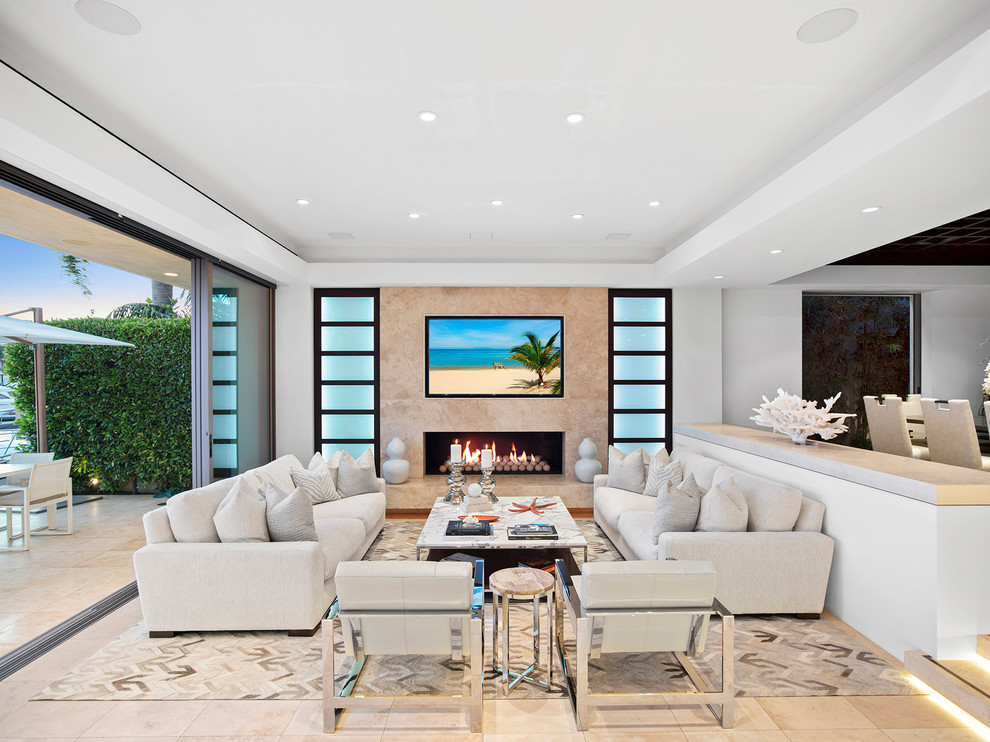 Photo of a tropical living room in Orange County with white walls, a ribbon fireplace and beige floor.