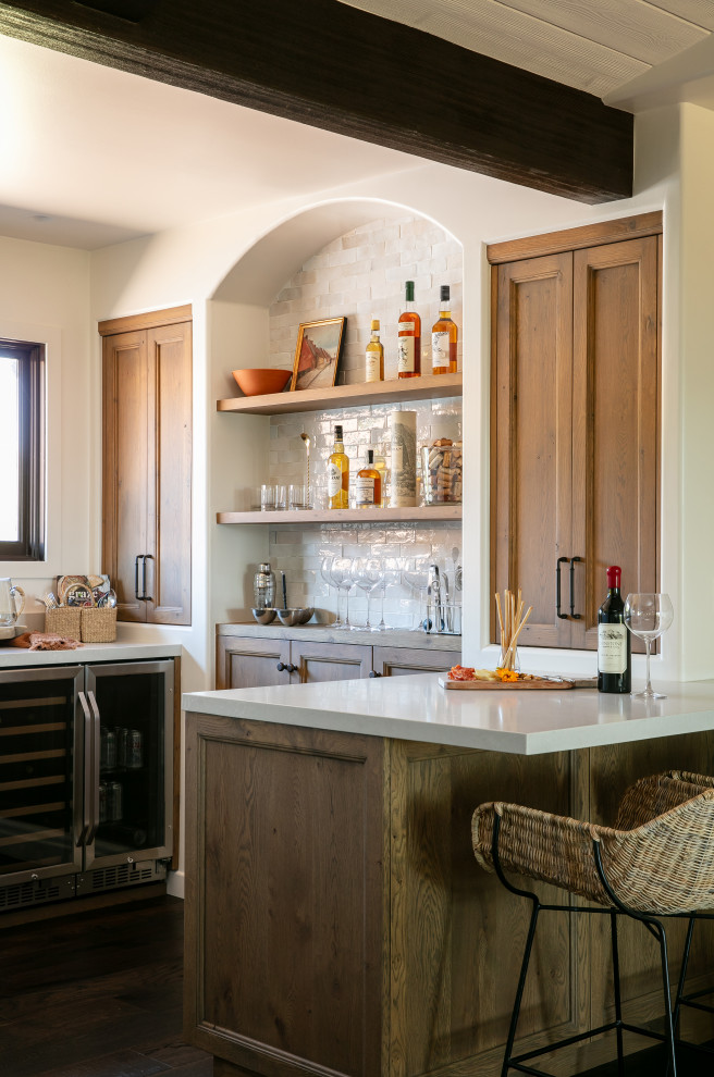 Small tuscan u-shaped dark wood floor and brown floor wet bar photo in Santa Barbara with an undermount sink, recessed-panel cabinets, medium tone wood cabinets, quartz countertops, white backsplash and beige countertops