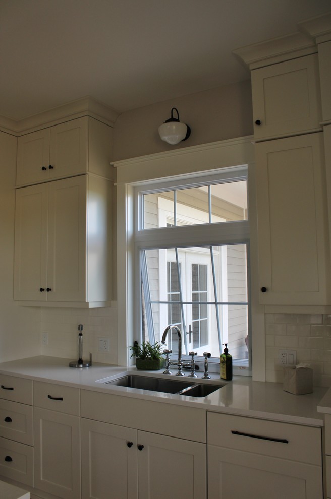 Example of a large transitional l-shaped eat-in kitchen design in Toronto with an undermount sink, shaker cabinets, white cabinets, quartz countertops, white backsplash, stainless steel appliances and an island