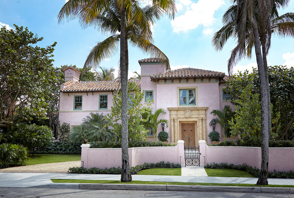 Inspiration for a mediterranean two-storey pink house exterior in Miami with a hip roof and a tile roof.