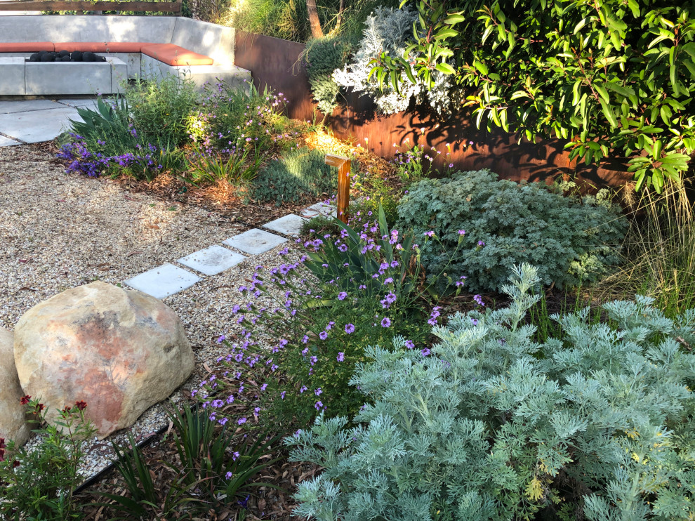 Idee per un grande giardino xeriscape design esposto in pieno sole dietro casa in primavera con un focolare, pavimentazioni in cemento e recinzione in metallo