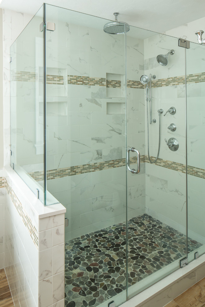 This is an example of a transitional master bathroom in Boston with recessed-panel cabinets, medium wood cabinets, a corner shower, multi-coloured tile and pebble tile floors.