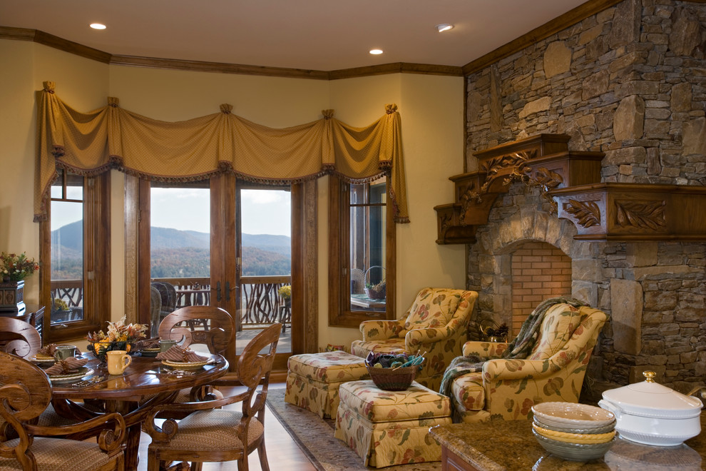 Photo of a mid-sized country dining room in Other with beige walls, medium hardwood floors, a stone fireplace surround and a standard fireplace.