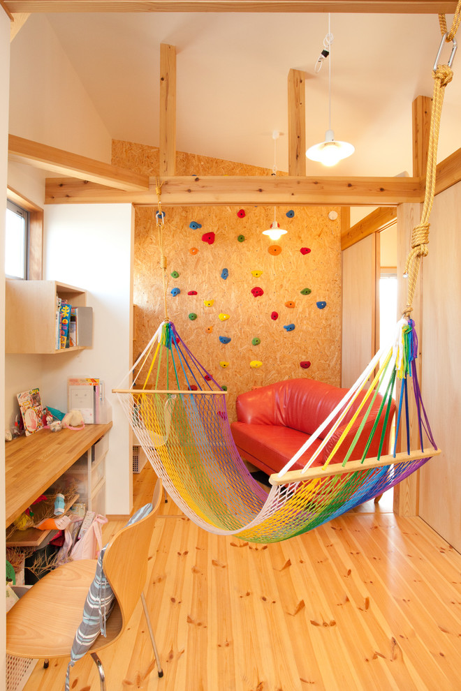 Photo of a mid-sized eclectic gender-neutral kids' playroom for kids 4-10 years old in Other with white walls and medium hardwood floors.
