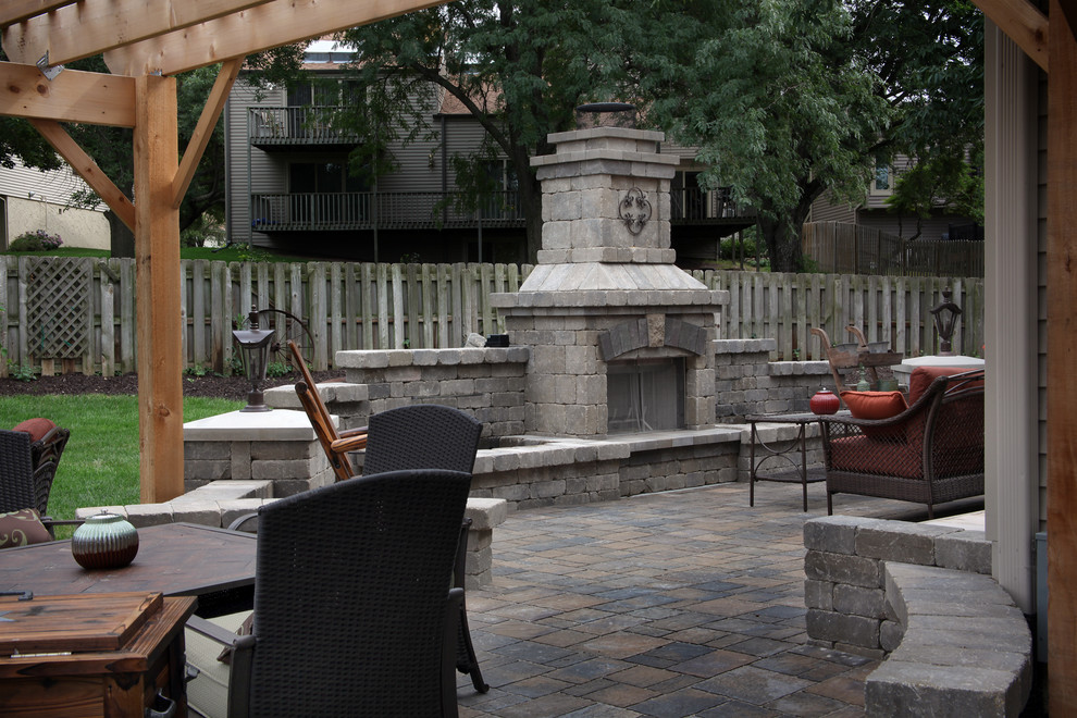Photo of a large traditional backyard patio in Omaha with a fire feature, concrete pavers and a pergola.
